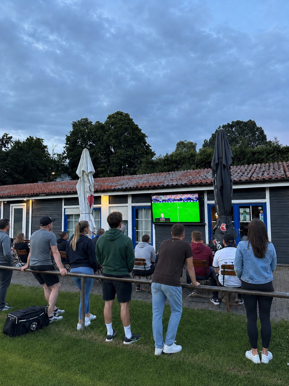 Gäste verfolgen gemeinsam ein Fußballspiel auf der Terrasse